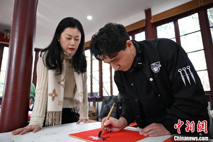 1月20日，外籍留學(xué)生在西泠印社社員李硯指導(dǎo)下寫福。當(dāng)日，來自巴西、馬來西亞、加納、哈薩克斯坦的外籍留學(xué)生在浙江杭州西泠印社體驗(yàn)福貼、春聯(lián)和篆刻，感受古老的中國傳統(tǒng)文化。中新社記者 王剛 攝