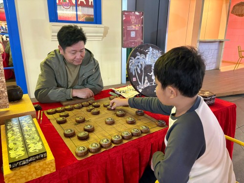 柯秋楓與市民下椰雕象棋。人民網(wǎng) 陳葉欣攝