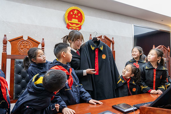 圖②：干警向同學(xué)們介紹法袍。