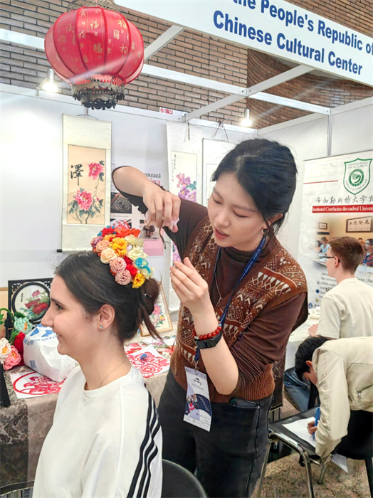 展覽正值羅馬尼亞迎春花節(jié)，國(guó)際中文教師志愿者潘婧穎向游客們介紹了國(guó)家非物質(zhì)文化遺產(chǎn)——福建泉州的簪花文化。布加勒斯特大學(xué)孔子學(xué)院供圖。