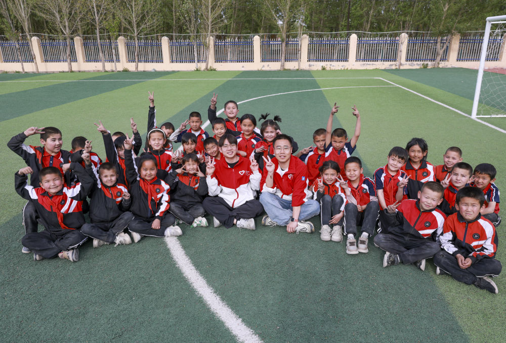 4月23日，在新疆克州阿圖什市哈拉峻鄉(xiāng)謝依特小學，支教教師王俊文（中左）、李軻凡（中右）和學生在一起。